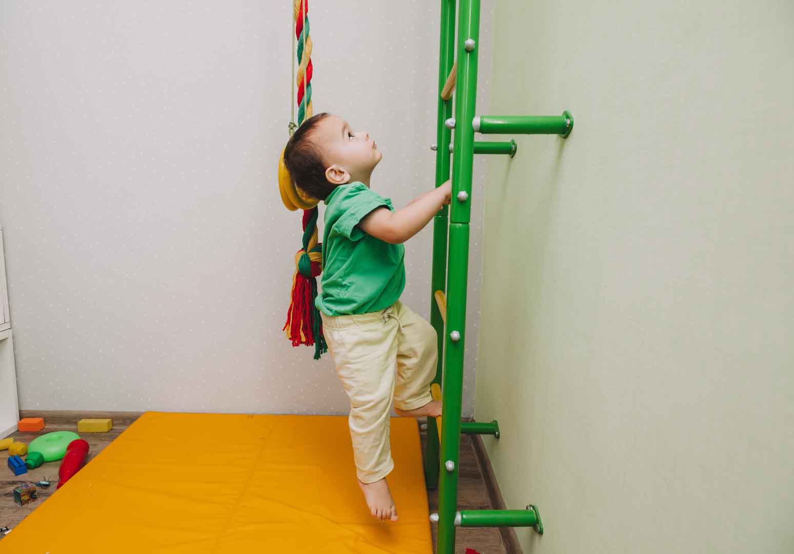 Child developing gross motor skills through climbing activity during occupational therapy session at OrbRom Center Phnom Penh