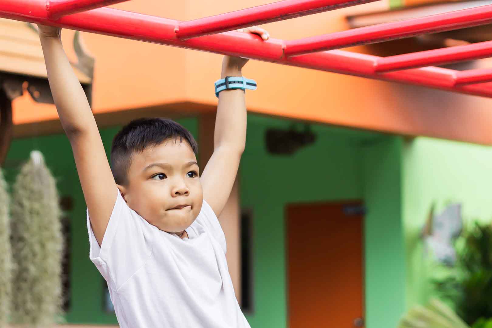 A determined child working on building upper body strength through play activities during occupational therapy at OrbRom Center in Phnom Penh.