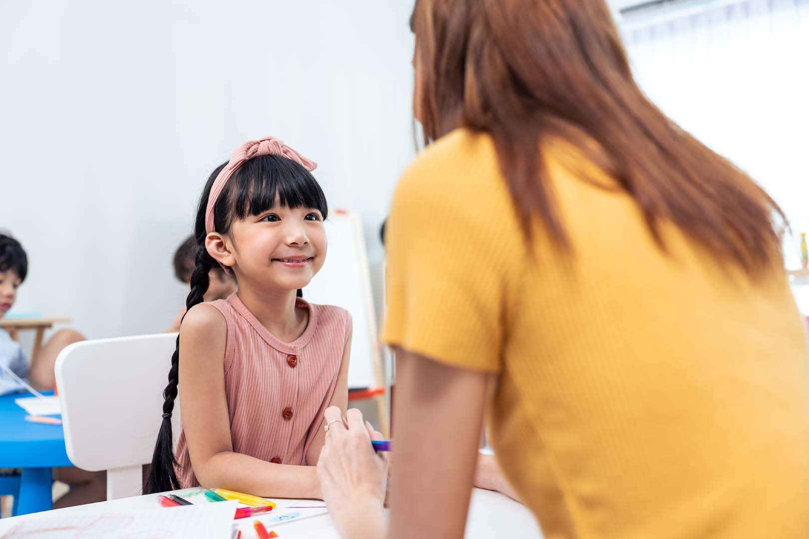 A smiling therapist interacting with a child during a creative activity, demonstrating trust and connection that support speech therapy success.