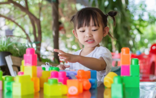 Young girl in Phnom Penh development school engaging in structured play with colorful blocks for cognitive skill building