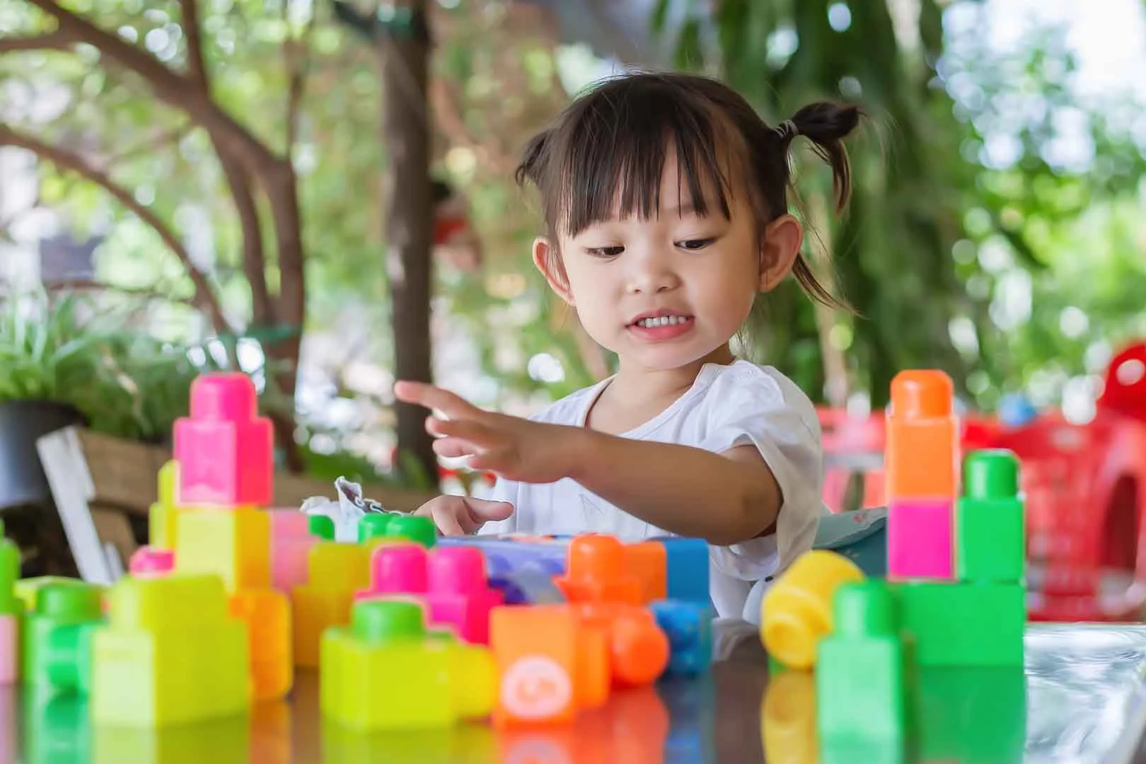 Young girl in Phnom Penh development school engaging in structured play with colorful blocks for cognitive skill building