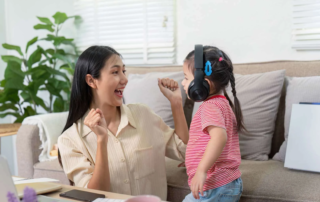 Smiling therapist and young girl with sensory headphones celebrating progress during an occupational therapy session in Phnom Penh