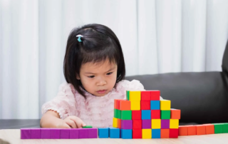 Young girl in Phnom Penh development school concentrating on building colorful blocks to build task persistence and problem-solving skills