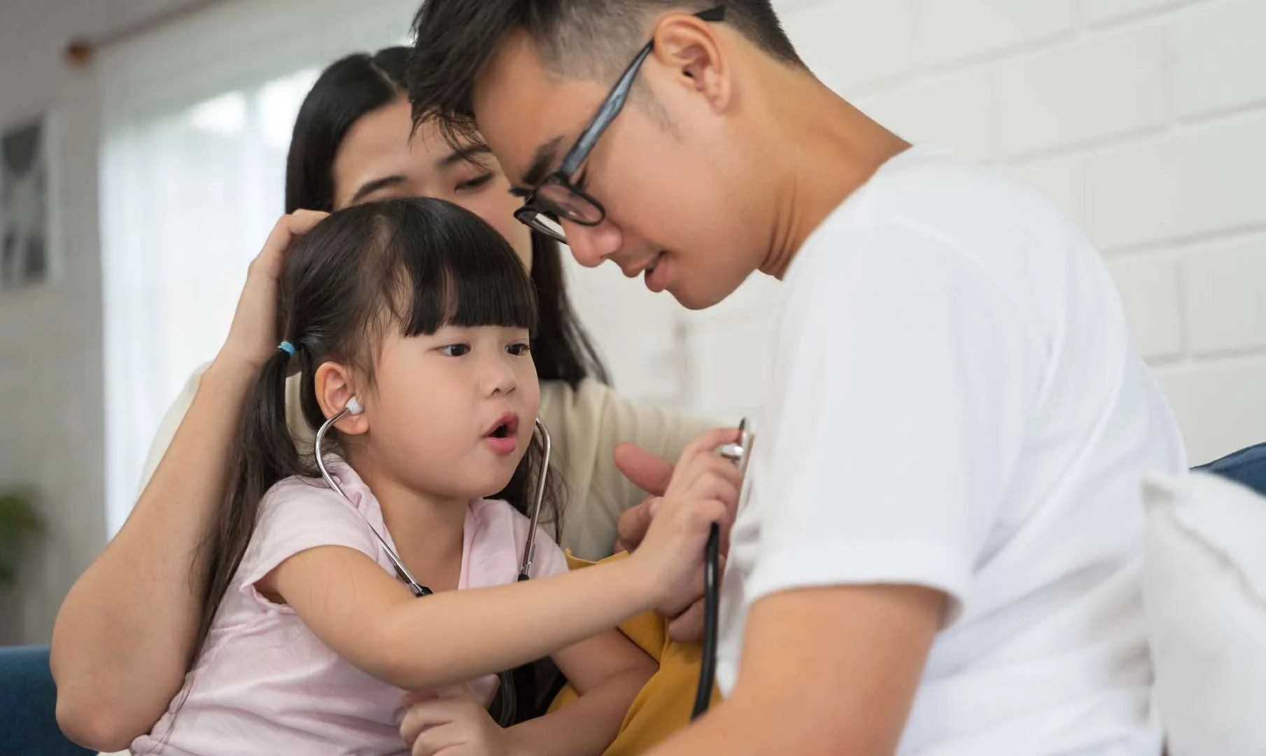Child engaging in a playful activity with parents during a developmental session at a clinic supporting kids in Phnom Penh