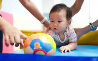 Young child participating in occupational therapy activities to improve motor skills, with colorful toys and supportive therapist in Phnom Penh.