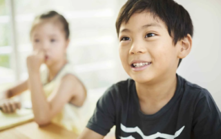Young boy smiling confidently during a classroom-based speech therapy session at OrbRom Center in Phnom Penh