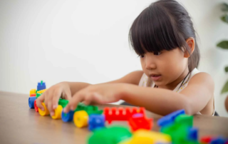 Young girl in Phnom Penh development school engaged in manipulative play with colorful building blocks for skill development