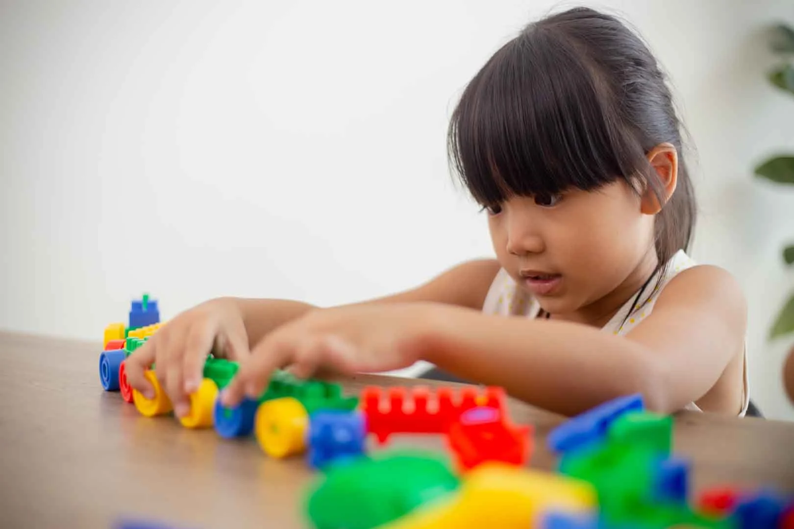 Young girl in Phnom Penh development school engaged in manipulative play with colorful building blocks for skill development