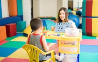 Therapist using alphabet stencil and play tools with child in colorful occupational therapy room in Phnom Penh