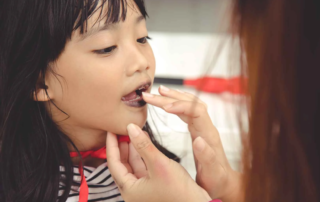 Speech therapist providing oral motor stimulation to a child’s mouth during a therapy session in Phnom Penh