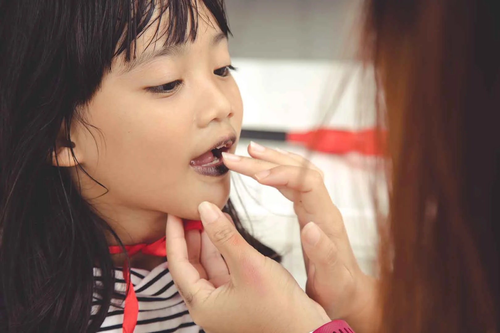 Speech therapist providing oral motor stimulation to a child’s mouth during a therapy session in Phnom Penh