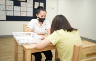 A teacher at OrbRom Center working one-on-one with a child during a personalized special education session in Phnom Penh.