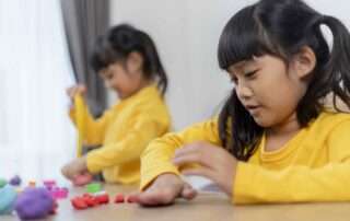 Two young girls in Phnom Penh development school playing with colorful dough to support sensory and fine motor development