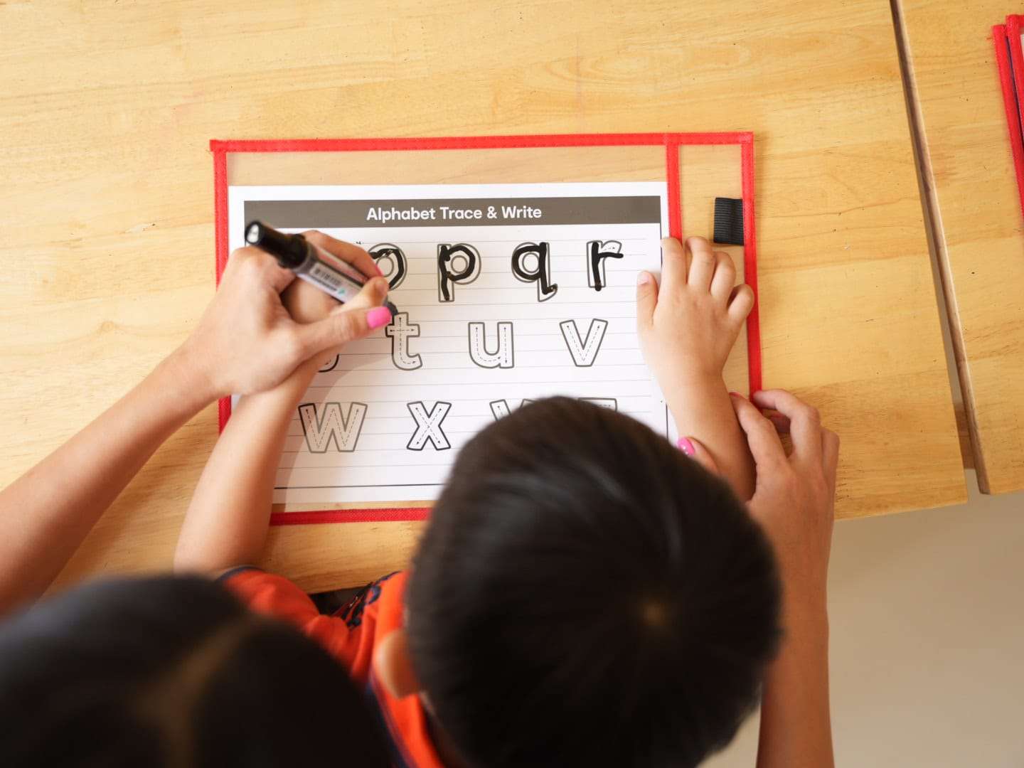 Occupational therapist guiding a child in tracing letters during a handwriting support session at OrbRom Center in Phnom Penh