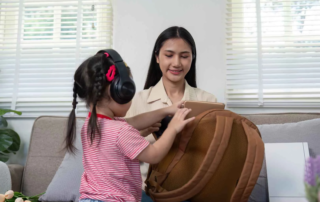 Child using noise-canceling headphones while preparing for a transition with caregiver support at OrbRom Center in Phnom Penh