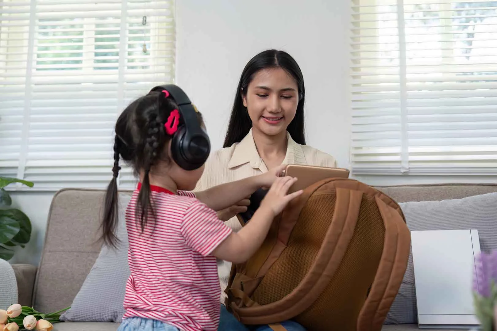 Child using noise-canceling headphones while preparing for a transition with caregiver support at OrbRom Center in Phnom Penh