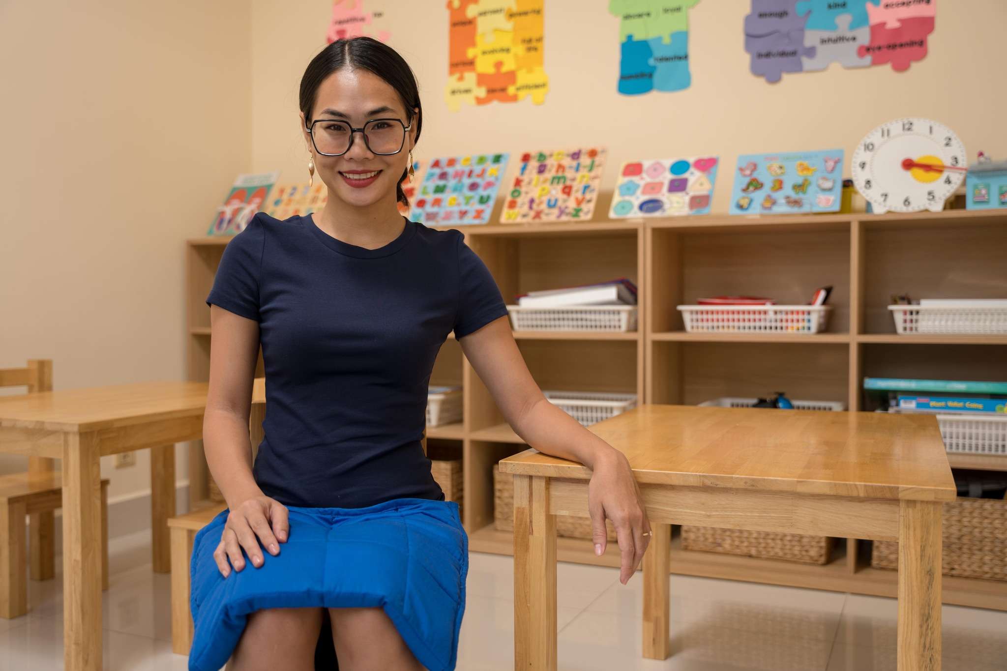 Special education teacher at OrbRom Center explaining the use of a weighted blanket for sensory regulation in Phnom Penh classroom