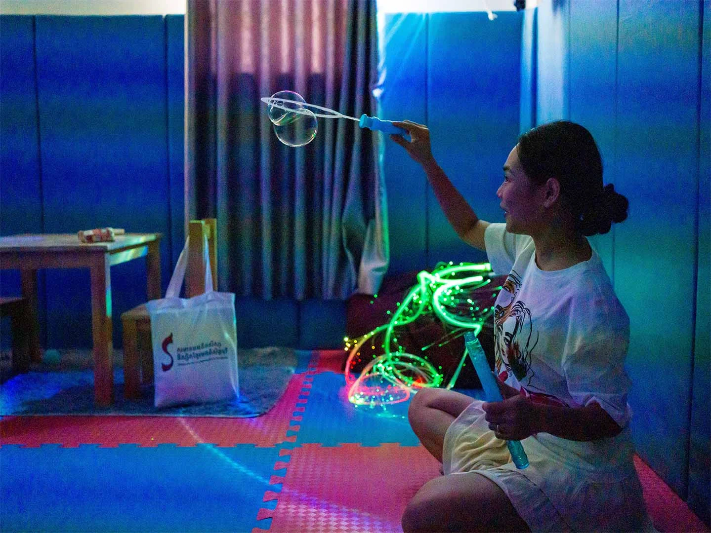 Therapist at OrbRom Center using bubble wands and fiber optic lights in a sensory room to support regulation in children with autism