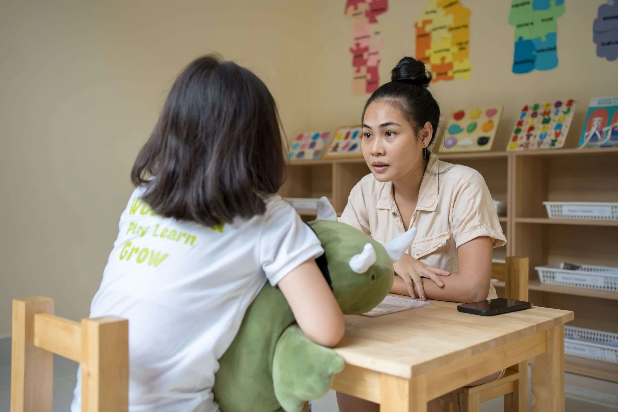 Therapy Phnom Penh A child holding a plush toy sits across from a therapist during a focused therapy session at a center in Phnom Penh.