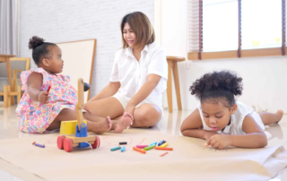 Two young children participating in creative fine motor play activities under the supervision of a therapist in Phnom Penh