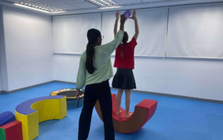 Therapist supporting a child during a balance activity at OrbRom Center Phnom Penh