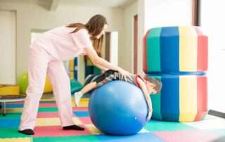 A child receiving sensory integration therapy on a large therapy ball during occupational therapy at OrbRom Center in Phnom Penh