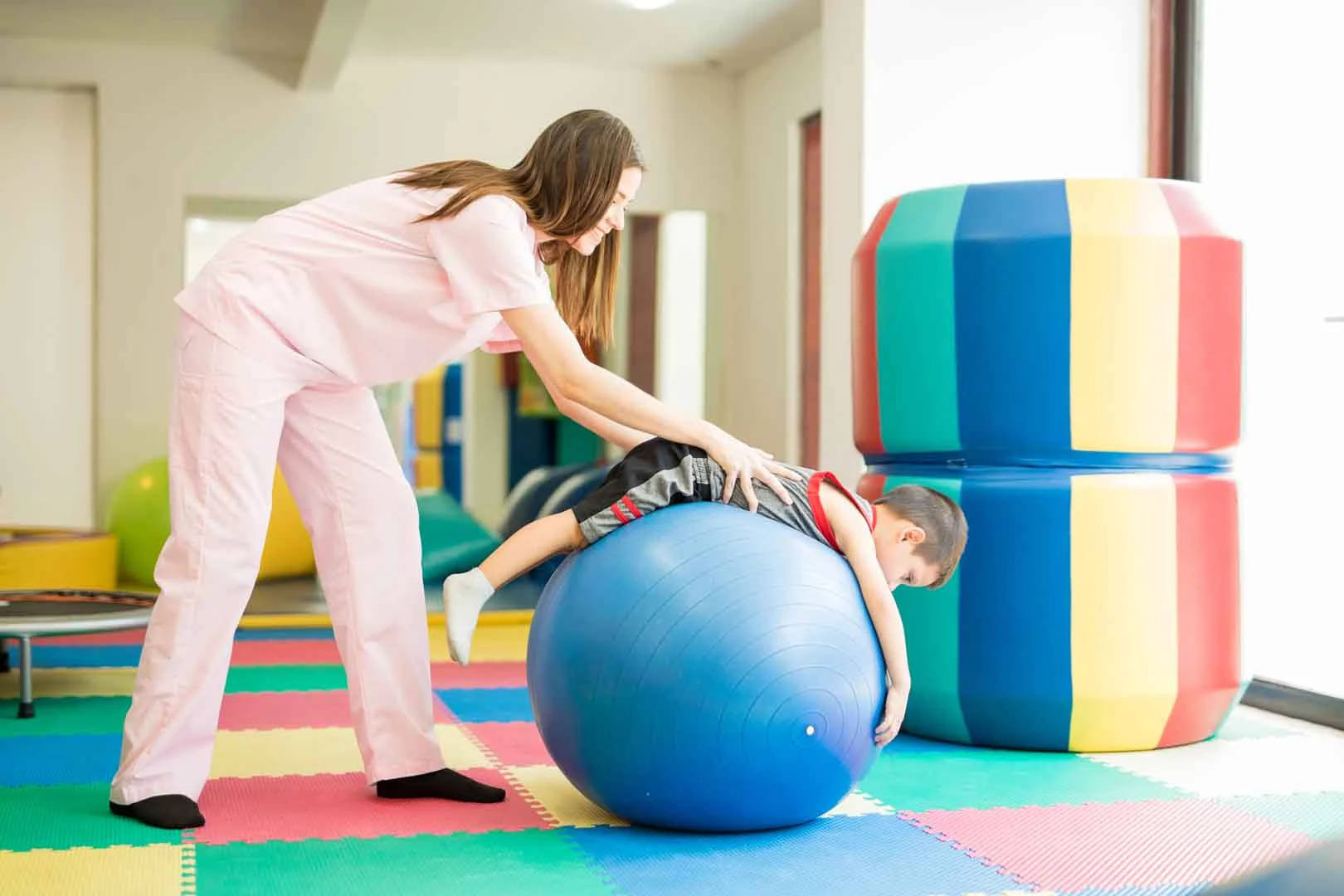A child receiving sensory integration therapy on a large therapy ball during occupational therapy at OrbRom Center in Phnom Penh