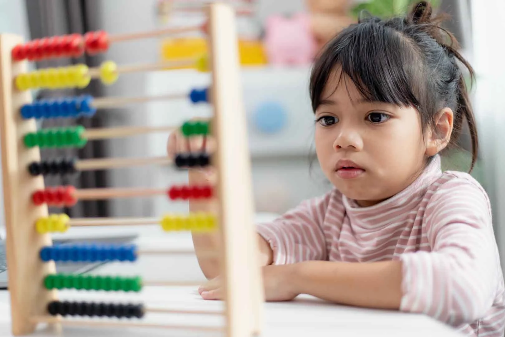 Young girl concentrating on abacus counting activity, showing early signs of potential learning challenges