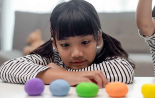Child focusing intently on colorful objects, illustrating early behavioral signs relevant to autism assessment