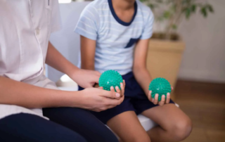 A therapist and child holding textured sensory balls during a self-regulation occupational therapy session in Phnom Penh