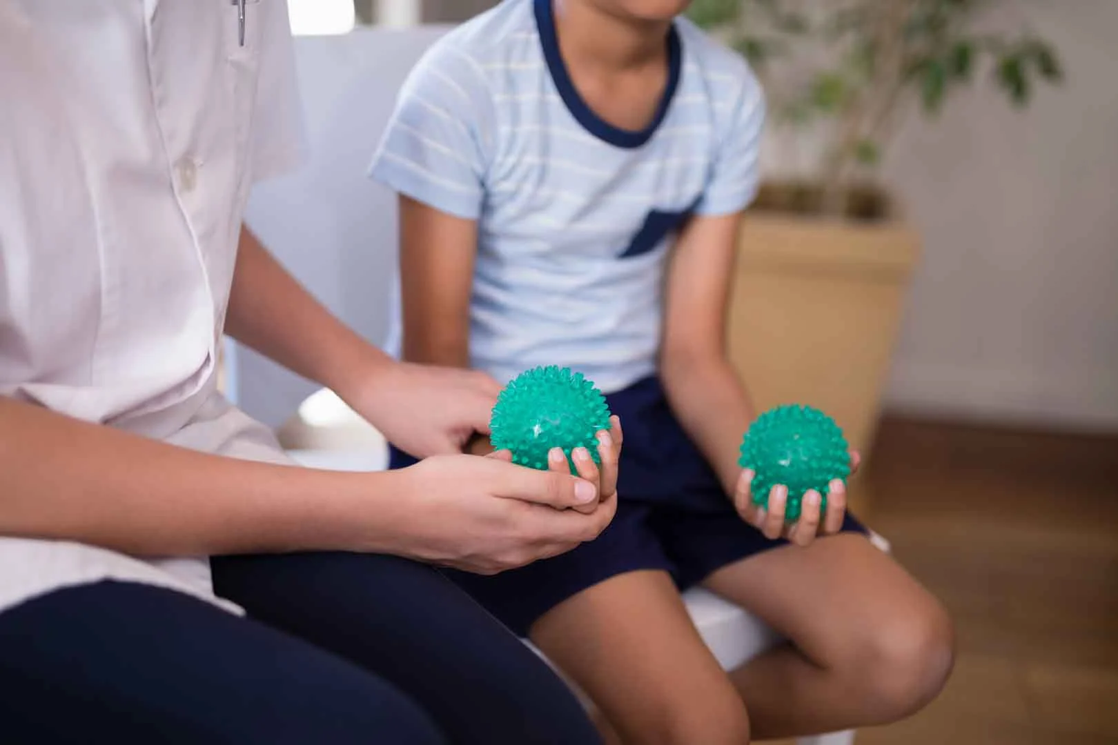 A therapist and child holding textured sensory balls during a self-regulation occupational therapy session in Phnom Penh