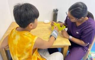 Child and occupational therapist at OrbRom Center using threading activity to improve fine motor skills