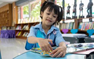 Young girl wearing a hearing aid engaging in a colorful puzzle activity, representing speech therapy support for hearing-impaired children in Phnom Penh