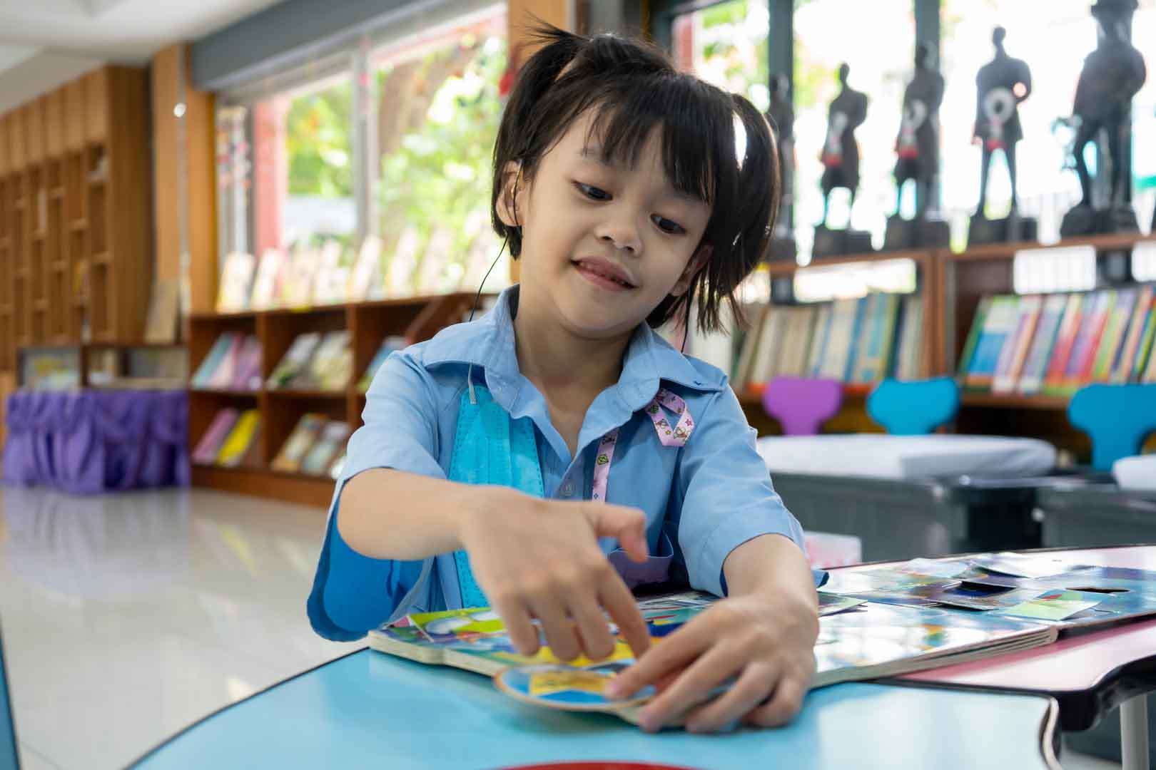 Young girl wearing a hearing aid engaging in a colorful puzzle activity, representing speech therapy support for hearing-impaired children in Phnom Penh