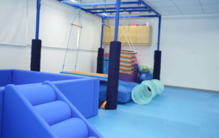 Indoor sensory room at OrbRom Center in Phnom Penh featuring swings, padded climbing steps, tunnels, therapy balls, and soft play equipment used for occupational therapy sessions.