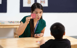 Special education teacher at OrbRom Center in Phnom Penh using visual card to support a child’s language development
