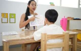 Educator at OrbRom Center Phnom Penh working one-on-one with child using alphabet chart in ADHD learning session