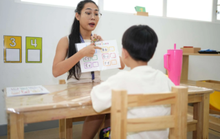 Educator at OrbRom Center Phnom Penh working one-on-one with child using alphabet chart in ADHD learning session