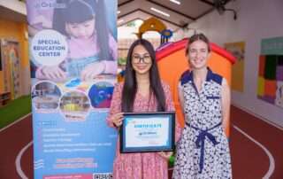 Two educators standing proudly with a certificate of appreciation from OrbRom Center, promoting teacher training for inclusive education in Cambodia