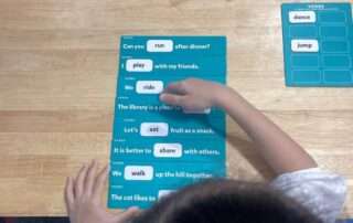 Child using verb identification cards during a learning activity at OrbRom Center in Phnom Penh