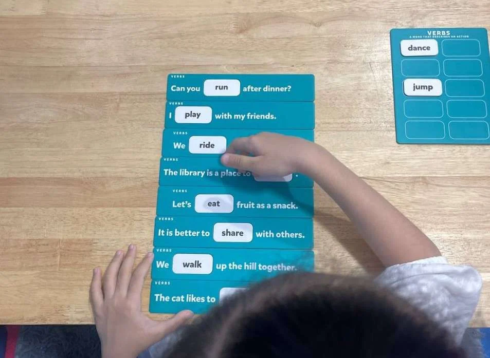 Child using verb identification cards during a learning activity at OrbRom Center in Phnom Penh
