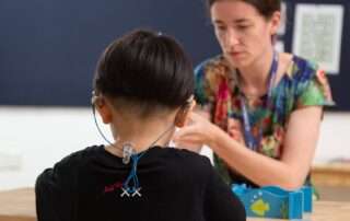 Student receiving teacher support for auditory processing challenges in a Phnom Penh classroom
