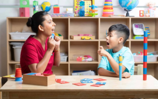Alt Text: A therapist uses a light-up visual cue while modeling lip movement to help a child improve pronunciation skills in therapy.