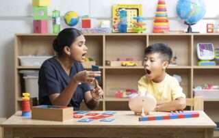 A therapist guides a young child through mouth movement exercises to improve speech clarity at OrbRom Center.