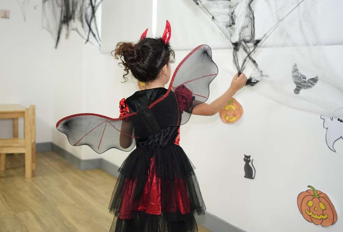 Children participating in a structured Halloween-themed preschool morning with decorated learning areas at OrbRom Center.
