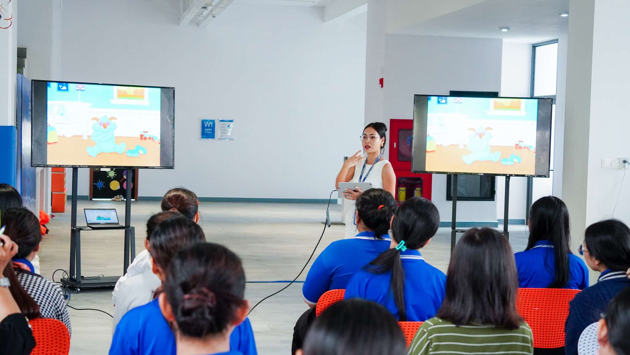 OrbRom Center specialist presenting to Bluebird British International School teachers about strategies for managing tantrums, with visual examples displayed on screens.