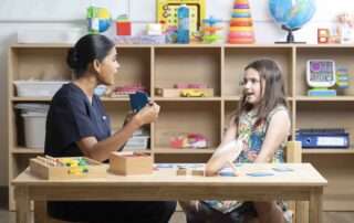 A speech therapist works one-on-one with a young girl during a language development session using visual cards at OrbRom Center in Phnom Penh.