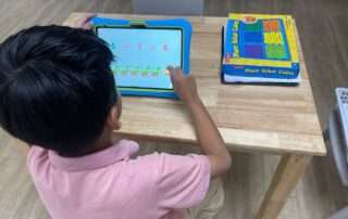 Child practicing early math skills on a tablet at OrbRom Center using Khan Academy Kids.