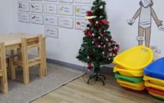 Teachers decorating a classroom Christmas tree and preparing a special needs preschool environment at OrbRom Center, with a cozy learning space ready for children’s holiday activities.