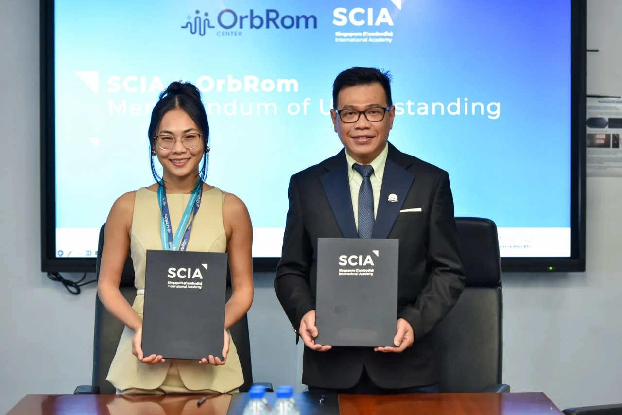 Representatives from Singapore Cambodia International Academy (SCIA) and CEO Sophaneth Heng, OrbRom Center holding signed Memorandum of Understanding documents for inclusive education collaboration.